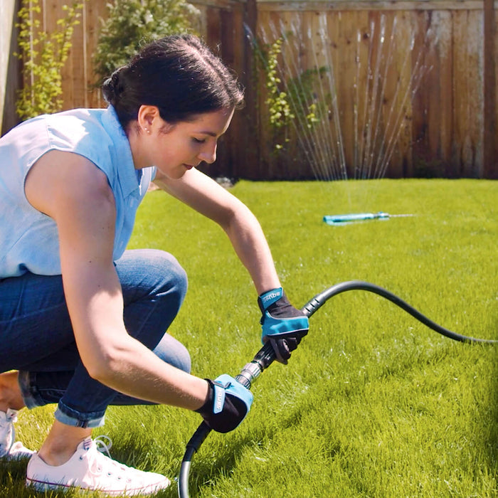 A woman connects the hose adapter to turn on a sprinkler.|42444323586298