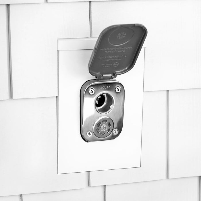 A slate gray house hydrant V2+ with the cover opened installed on white shingle siding with a mounting block.