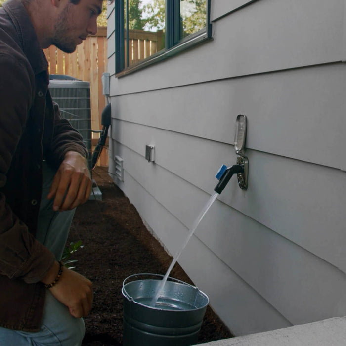 A man watching as a jet black removable faucet connector plugged into a brushed stainless house hydrant v2+ fills up a stainless steel bucket.|42444252578042