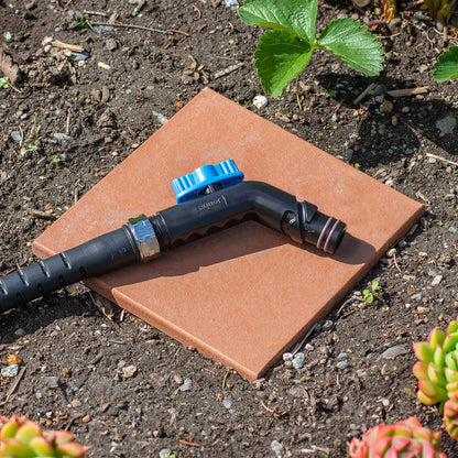A jet black removable faucet hose connector and hose in a garden.|42444252578042