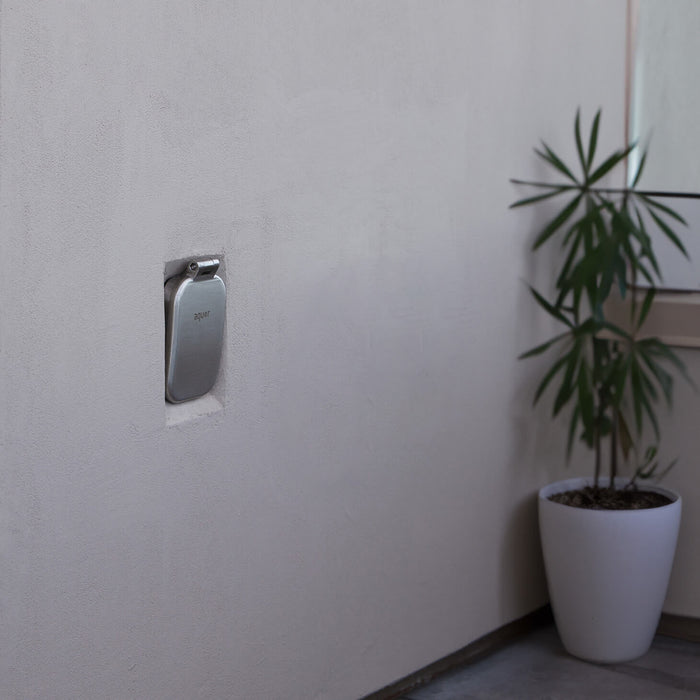 A brushed stainless v2+ debris cover shown on stucco.|47730985795834